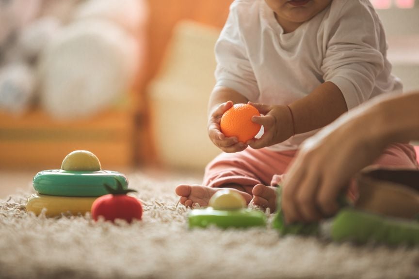 Baby sitzt auf dem Teppich und spielt