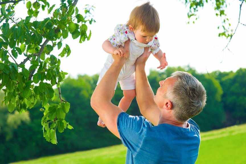 Vater hebt draussen Baby in die Luft