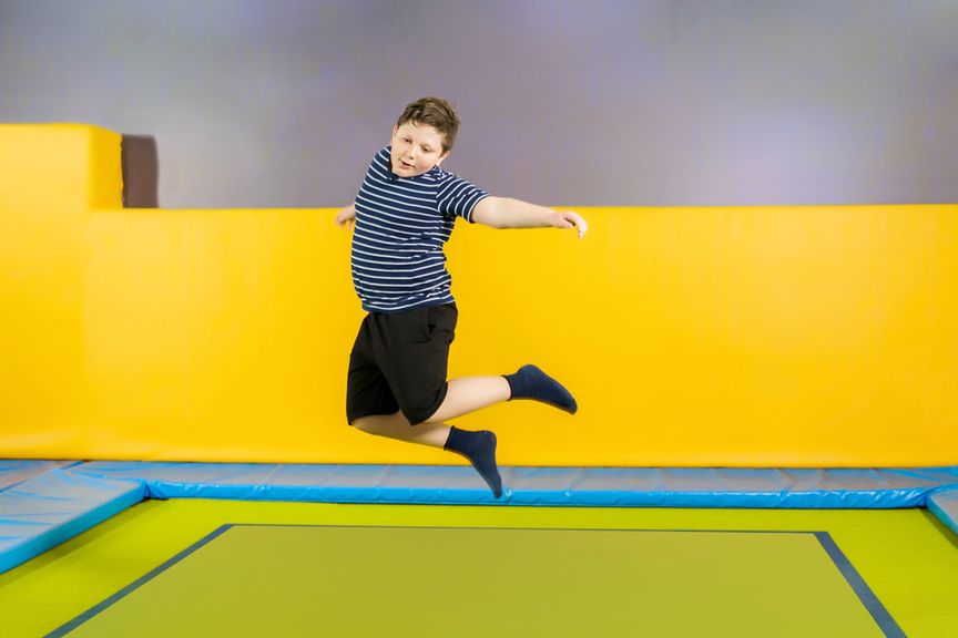 Übergewichtiges Kind springt in einer Trampolinhalle auf einem Trampolin