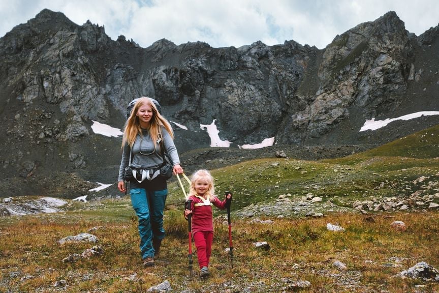 Mutter führt ihr Kind auf einer Bergwanderung am Laufgurt