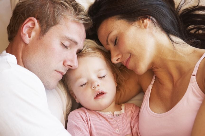 Eltern und Baby schlafen gemeinsam im Bett