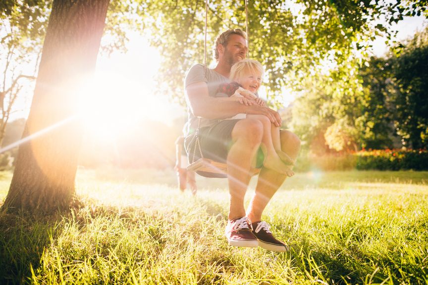 Vater und Sohn draussen auf der Schaukel in der Sonne