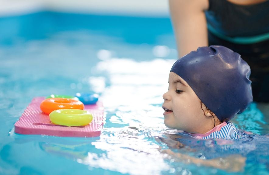 Kind beim Schwimmunterricht im Hallenbad