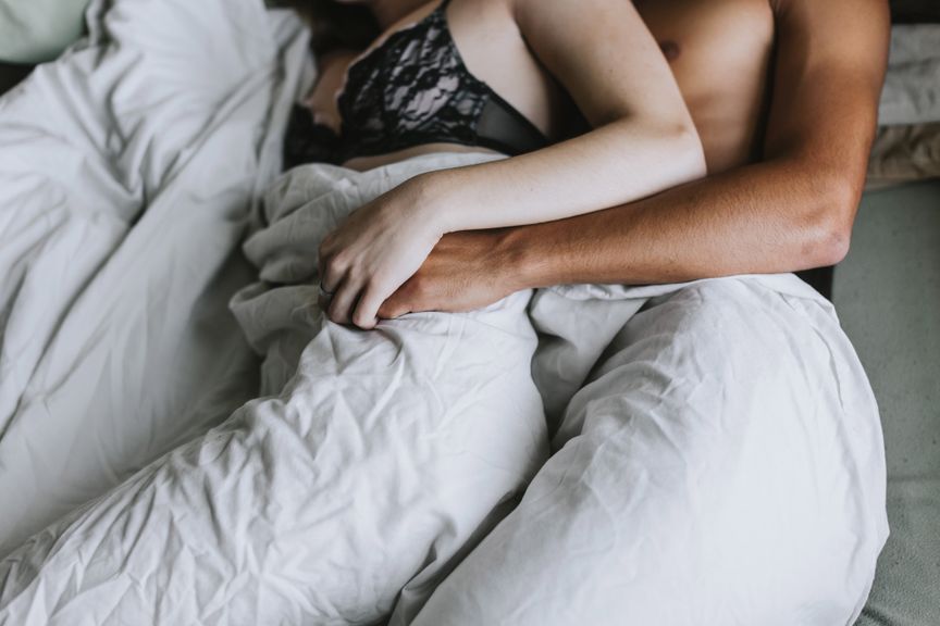 Mann und Frau im Bett, halten sich an den Händen
