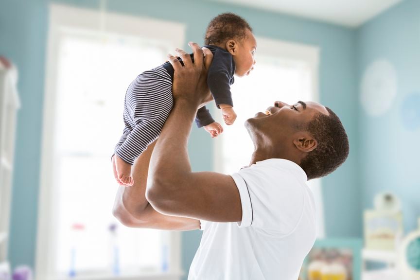 Ein lachender Vater hält sein Baby hoch