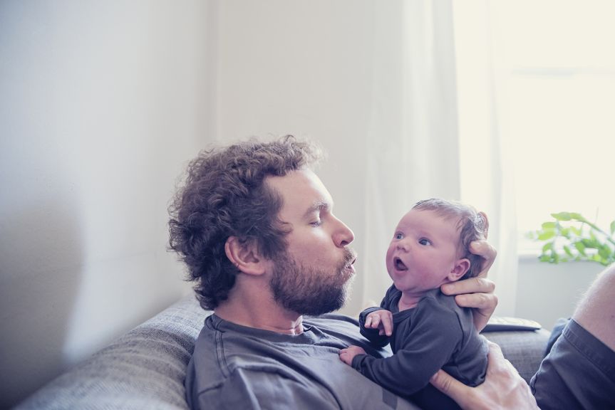 Vater sitzt mit Baby auf dem Sofa