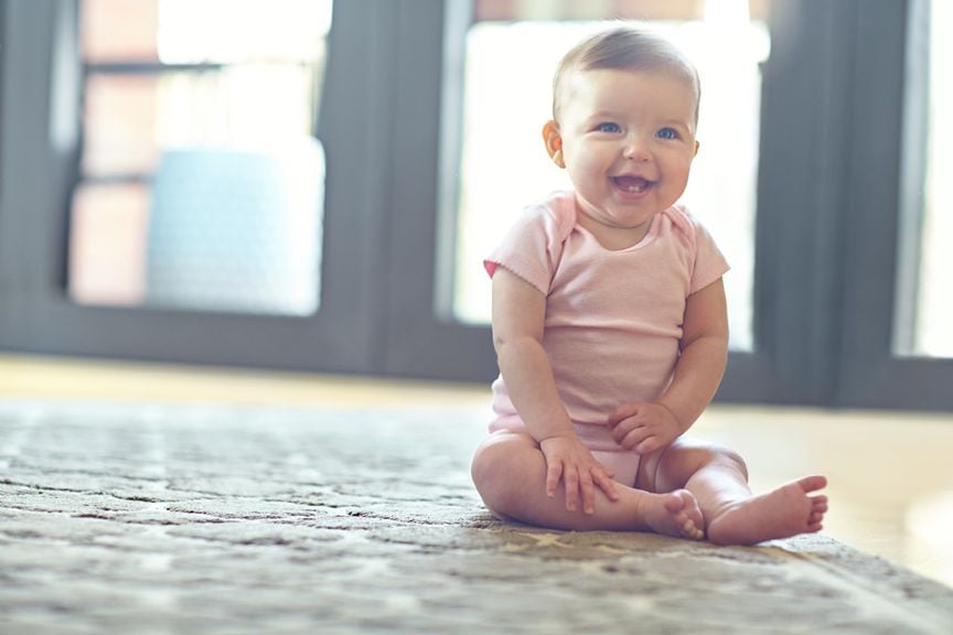 Strahlendes Baby sitzt auf dem Boden