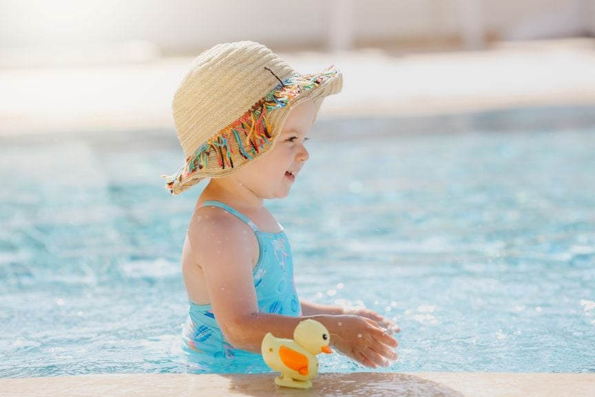 Kleinkind mit Sonnenhut im Schwimmbad