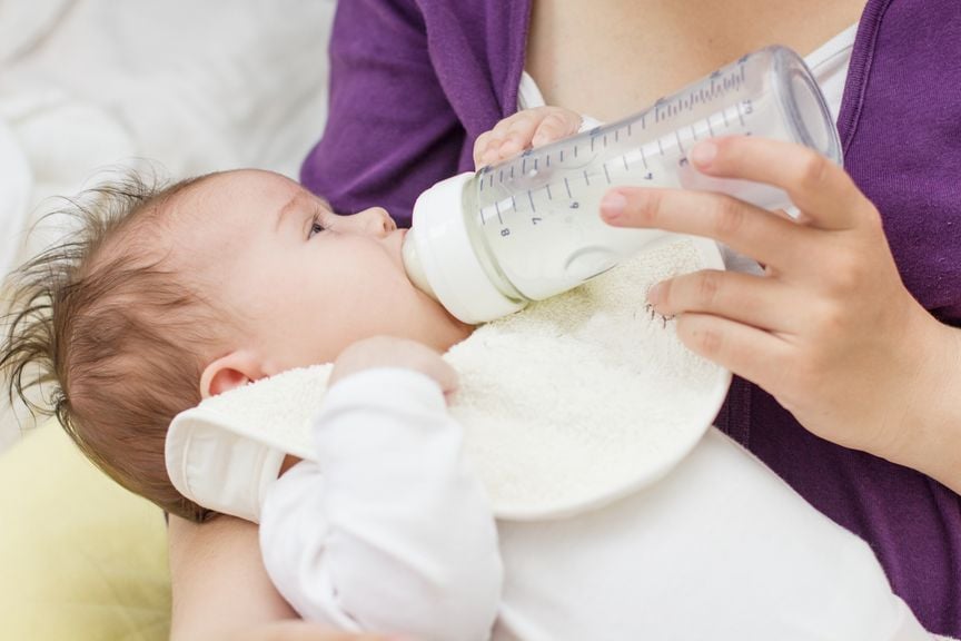 Baby im Arm der Mutter, wird mit dem Schoppen gefüttert