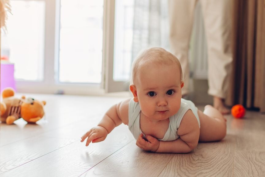 Baby krabbelt auf Holzboden