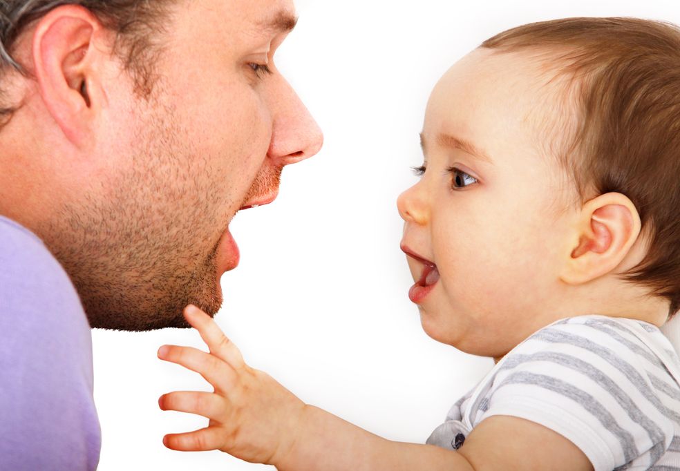 Vater und Baby sehen sich mit geöffnetem Mund an