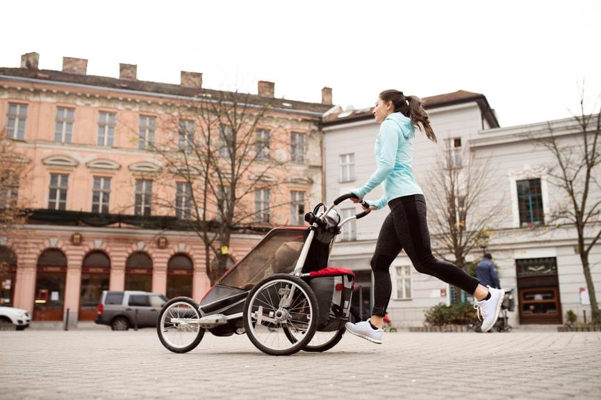 Frau joggt mit Kinderwagen
