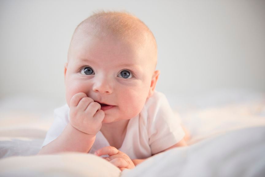 Baby auf dem Bauch mit der Hand im Mund