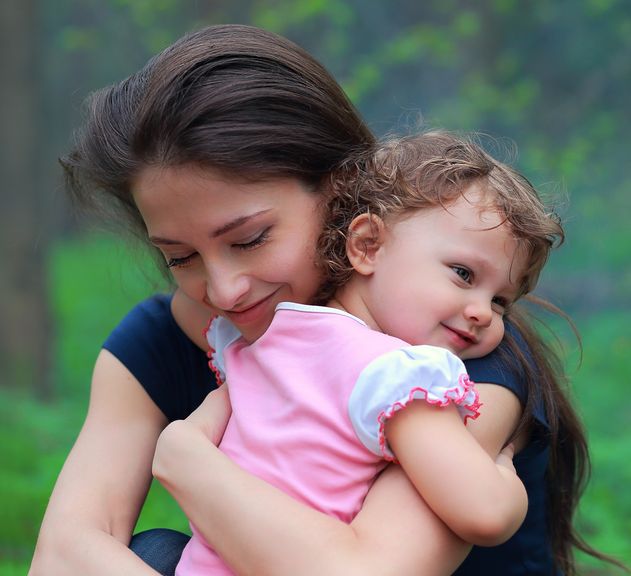 Mutter kniet vor Kind und nimmt es in den Arm