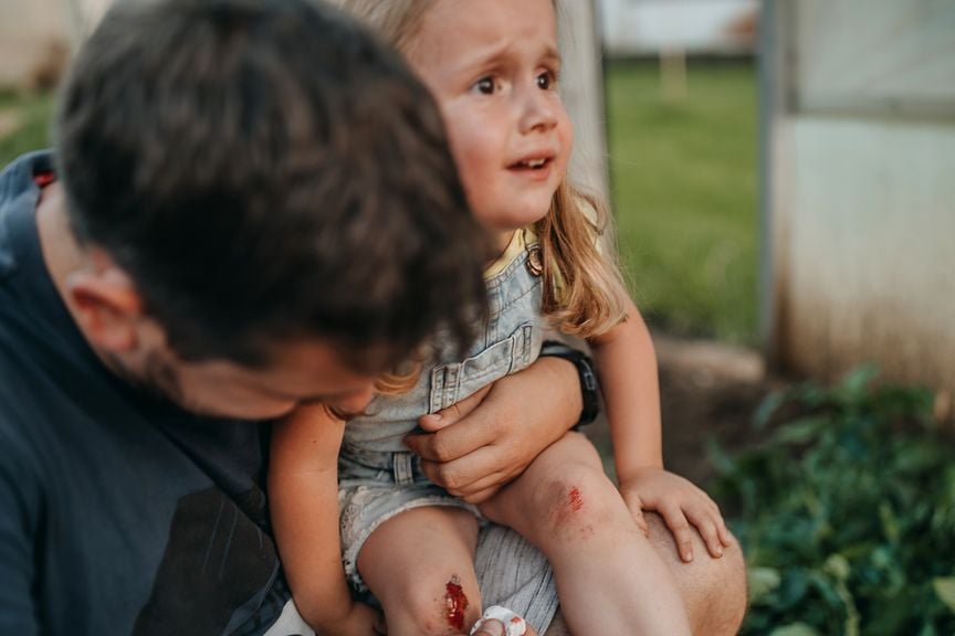 Vater versorgt blutende Wunde seiner Tochter