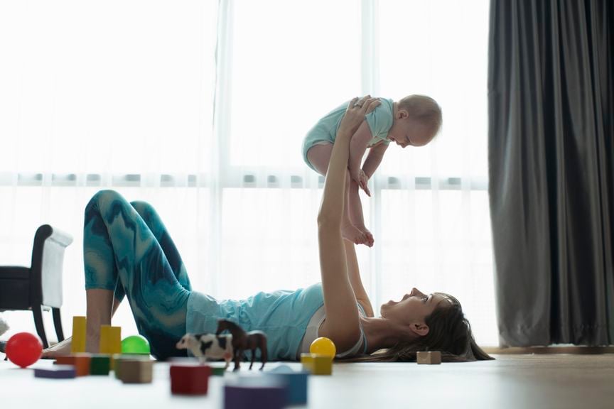 Mitter liegt am Boden und hebt das Baby in die Luft