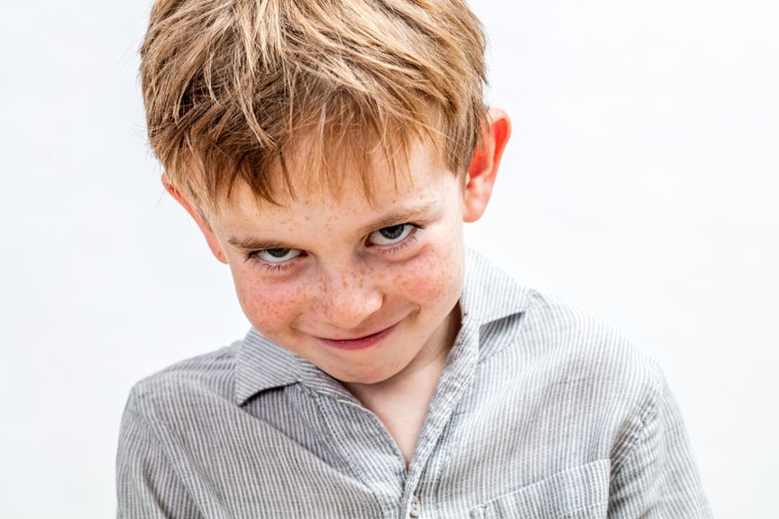 Kind mit Sommersprossen grinst frech in die Kamera