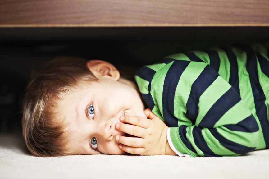 Kleines Kind versteckt sich unter dem Bett