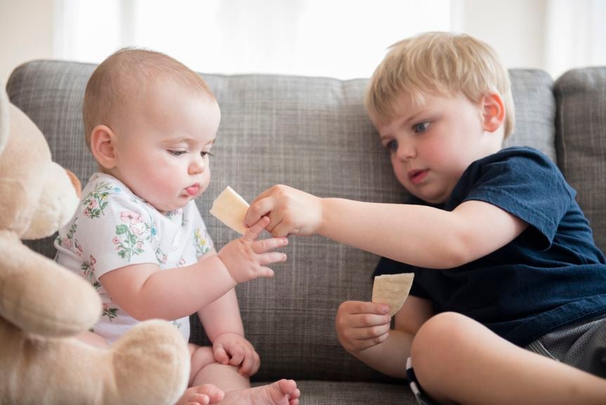 Junge teilt seine Crackers mit dem Baby