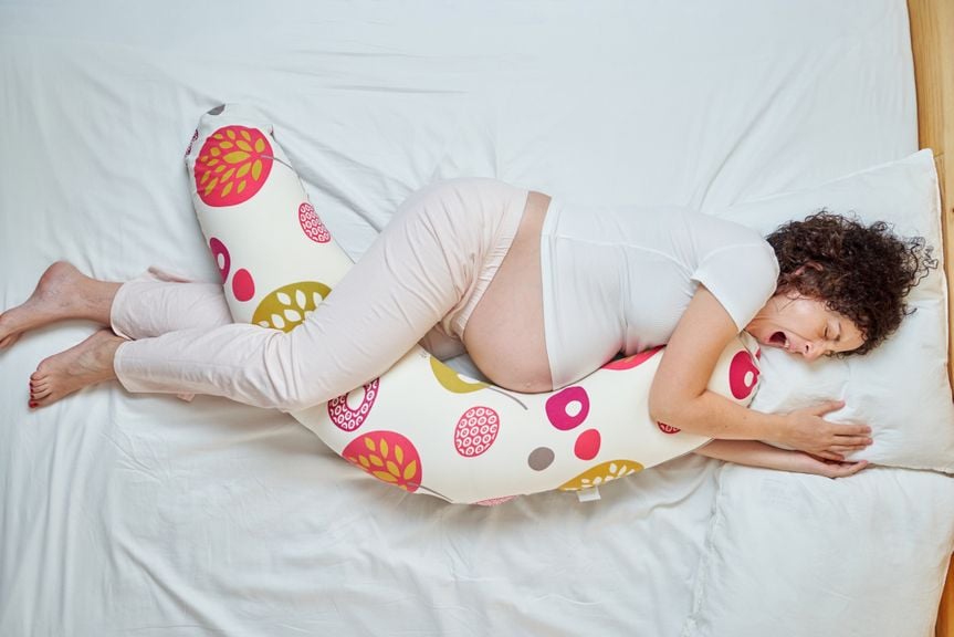 Schwangere im Bett mit Stillkissen