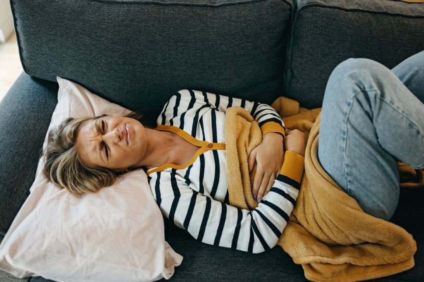 Frau mit Schmerzen liegt auf dem Sofa