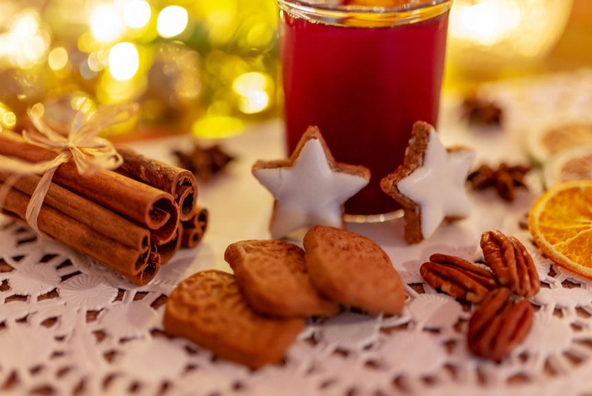 Arrangement mit Zimtstangen, Zimtsternen, Spekulatius, Pecannüssen, Orangenscheiben, Sternanis und Glühwein