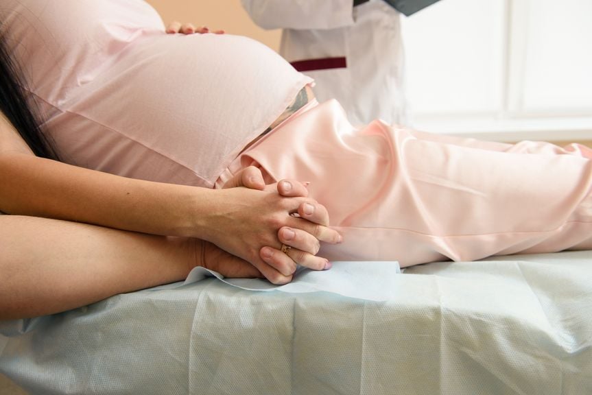 Schwangere im Bett, Mann hält ihre Hand