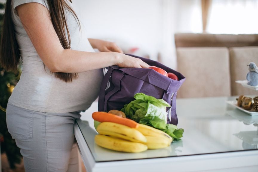Schwangere beim Auspacken von Früchten und Gemüse