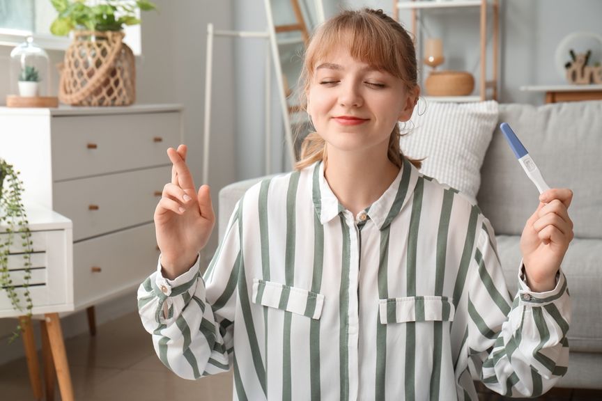 Frau kreuzt die Finger für Schwangerschaftstest