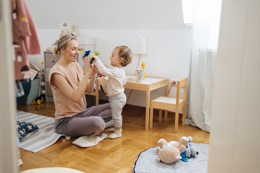 Mutter und KInd spielen im Kinderzimmer mit Handpuppen