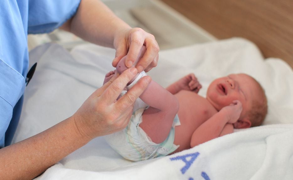 Pflegefachfrau macht eine Blutentnahme an der Ferse eines Neugeborenen