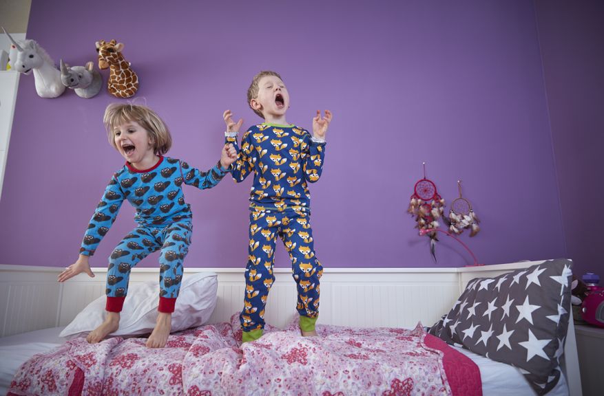 Kinder hüpfen im Pyjama auf dem Bett herum