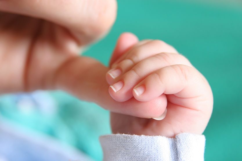 Babyhand hält kleinen Finger fest