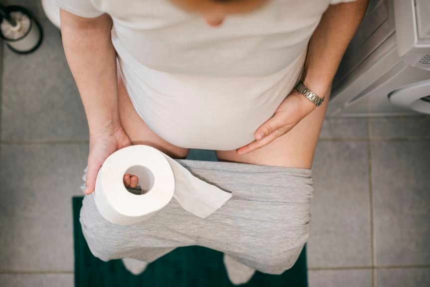 Schwangere sitzt auf dem WC