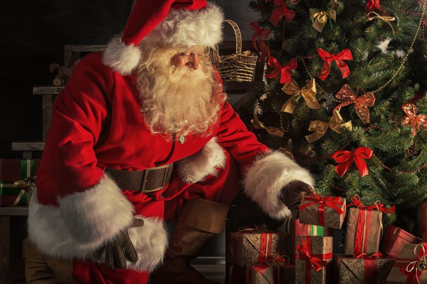 Weihnachtsmann vor Tannenbaum mit Geschenken