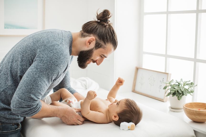 Vater wickelt sein Kind auf dem Wickeltisch