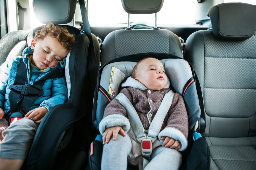 Kind und Baby schlafen in Kindersitzen im Auto