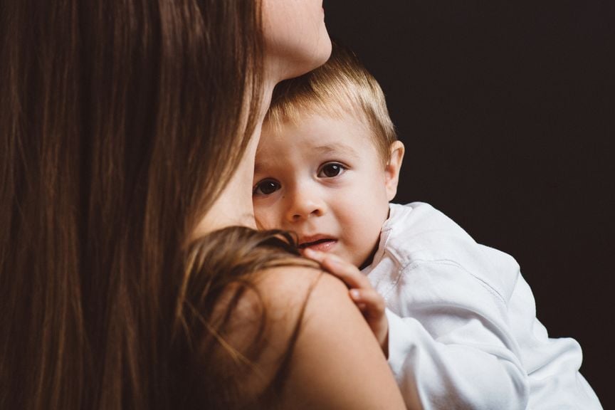 Baby auf dem Arm der Mutter schaut ängstlich und weinerlich