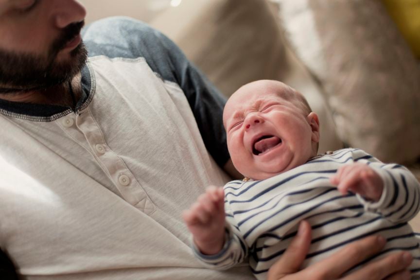 Weinendes Baby auf dem Arm vom Vater