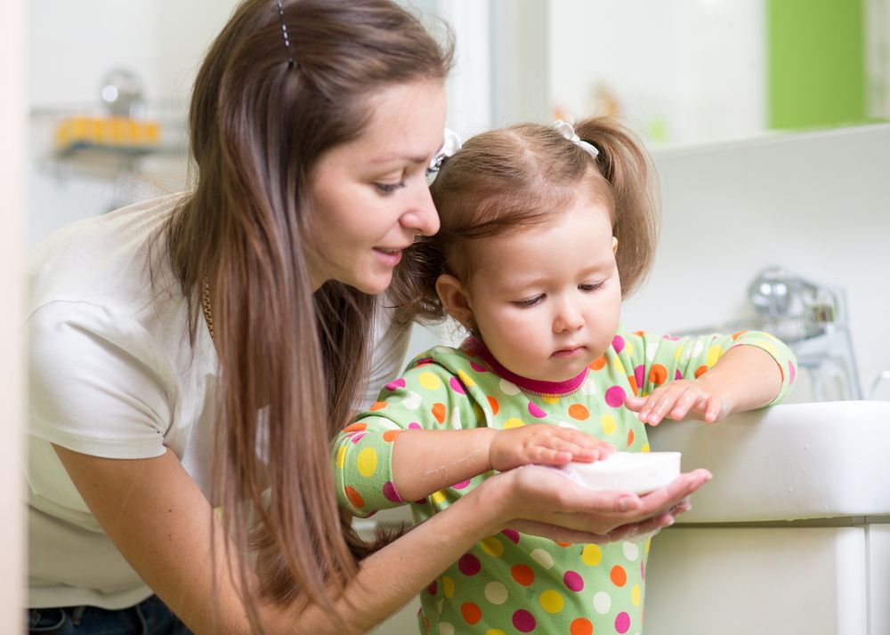 Mutter gibt Tochter die Seife zum Händewaschen