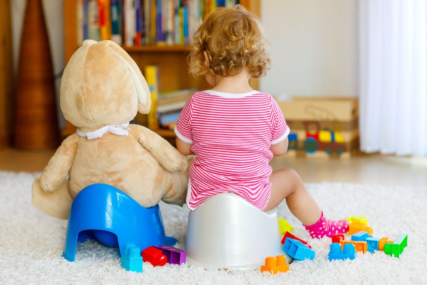 Kind und Teddy sitzen auf einem Töpfchen