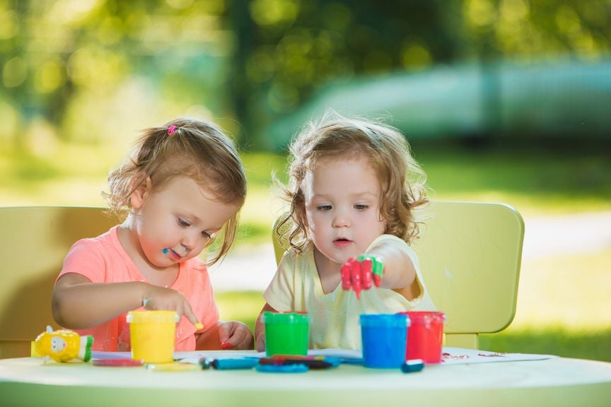 Zwei Kinder malen draussen mit Fingerfarben