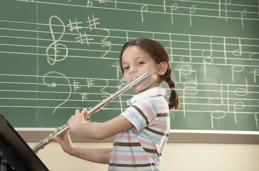 Kind in der Musikschule spielt die Querflöte