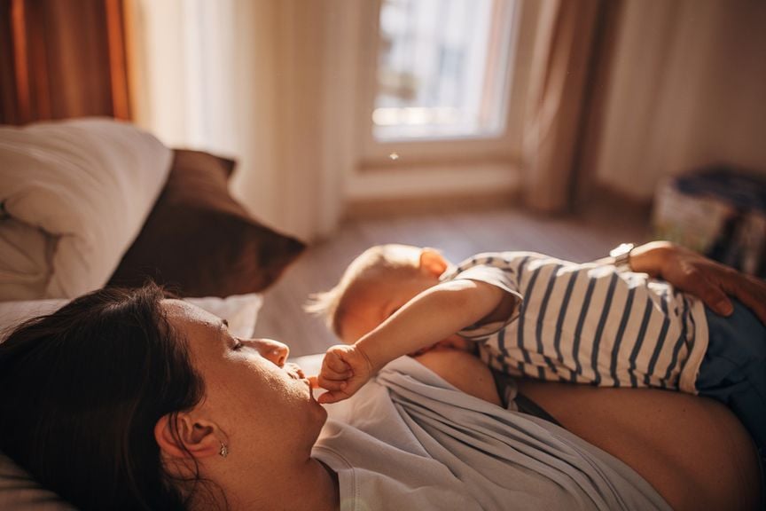 Baby, während des Stillens, mit dem Finger im Gesicht der Mutter