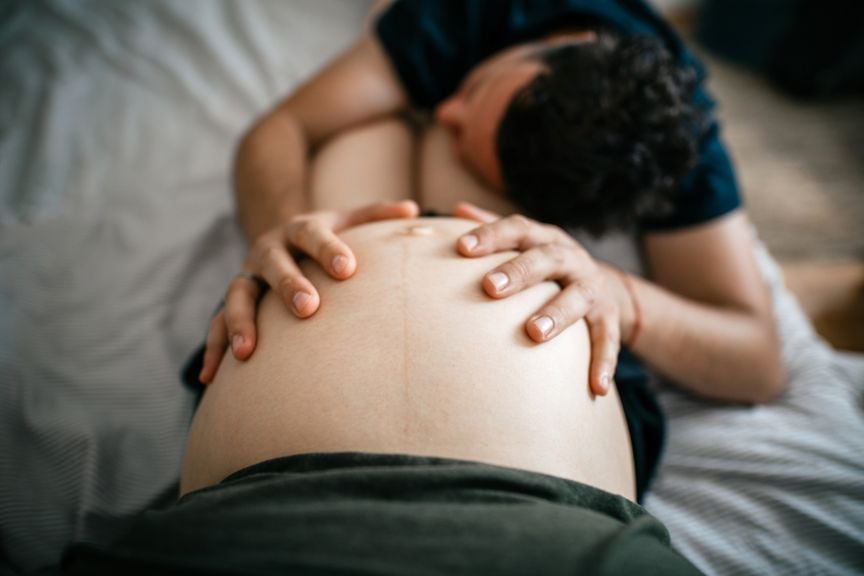 Partner hält die Hände auf den Bauch der Schwangeren