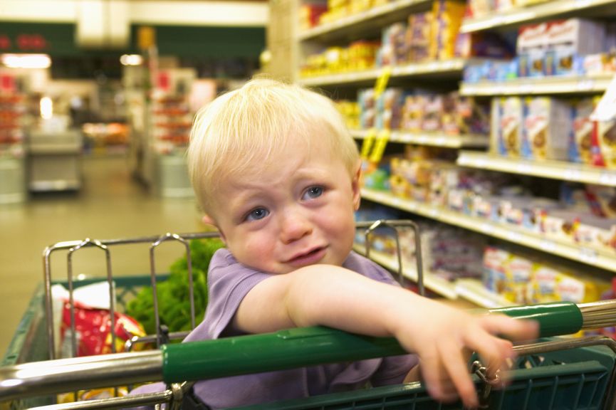 Kind quengelt im Einkaufswagen