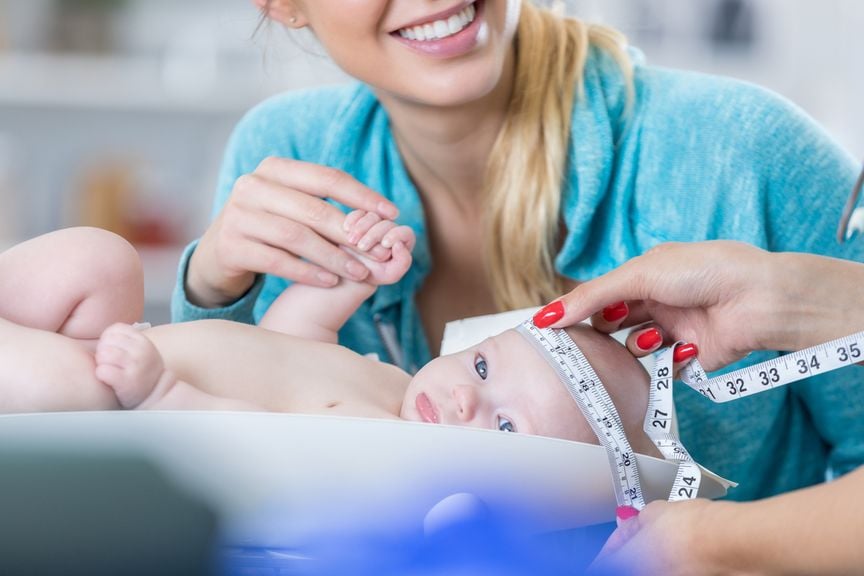 Mutter mit Baby beim Kinderarzt, Kopfumfang wird gemessen