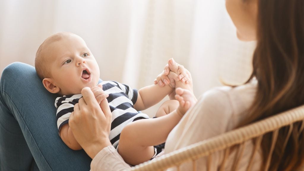 Baby liegt auf den Beinen seiner Mutter 