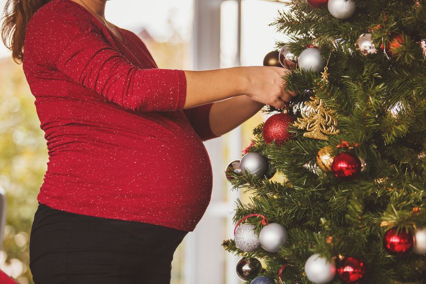 Schwangere dekoriert den Weihnachtsbaum