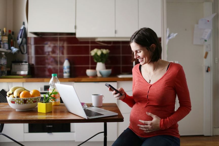 Schwangere an Handy und Laptop